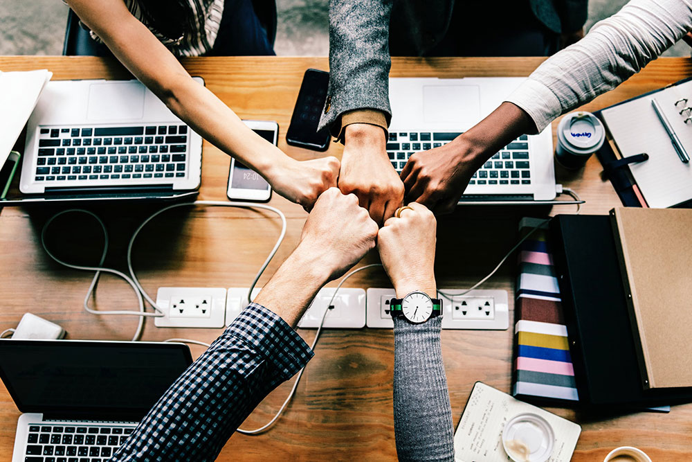 Team fist bump across a desk